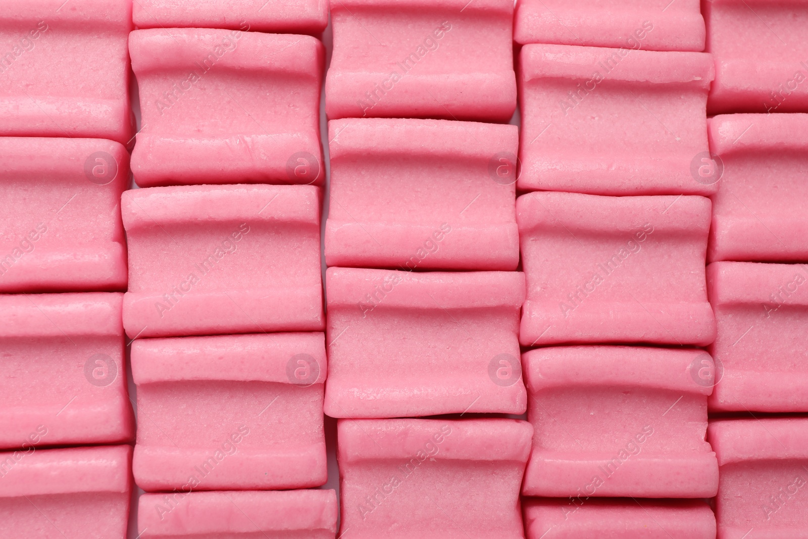 Photo of Tasty pink chewing gums as background, top view