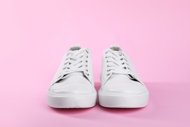 Photo of Pair of stylish white sneakers on pink background