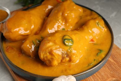 Tasty chicken curry, garlic and spice on grey textured table, closeup