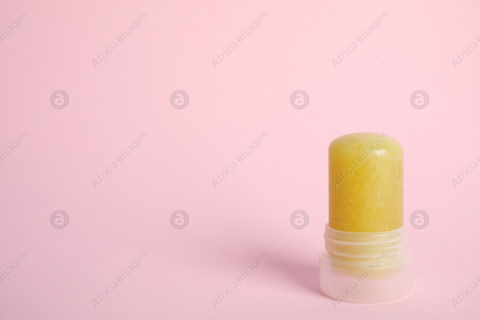 Photo of Natural crystal alum stick deodorant on pink background. Space for text