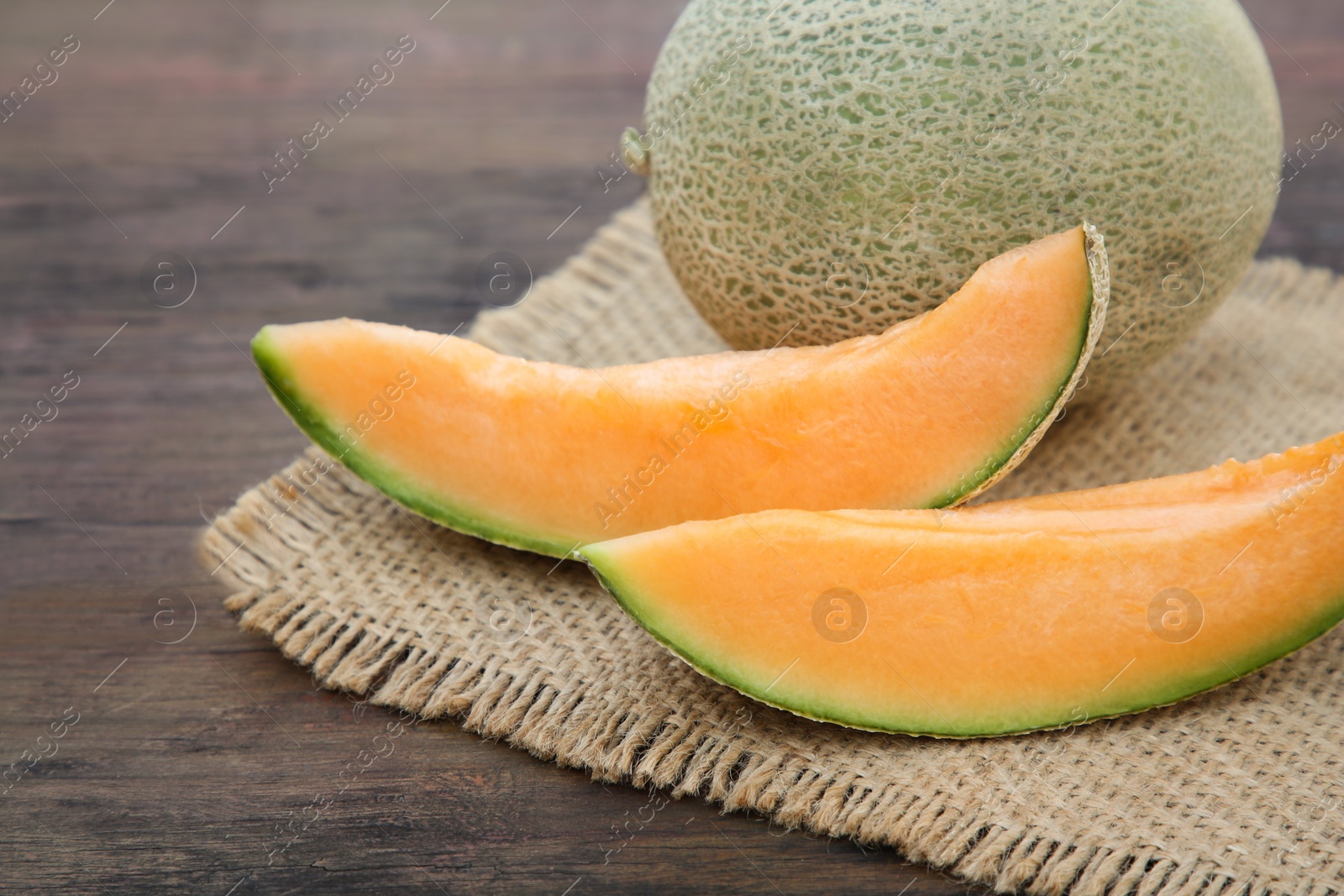 Photo of Cut and whole delicious ripe melons on wooden table, closeup