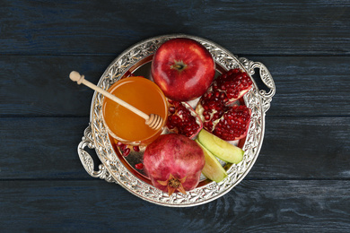 Photo of Honey, apples and pomegranate on dark blue wooden table, top view. Rosh Hashanah holiday