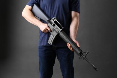 Photo of Assault gun. Man holding rifle on dark background, closeup