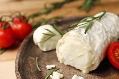 Photo of Delicious goat cheese with rosemary on wooden board, closeup