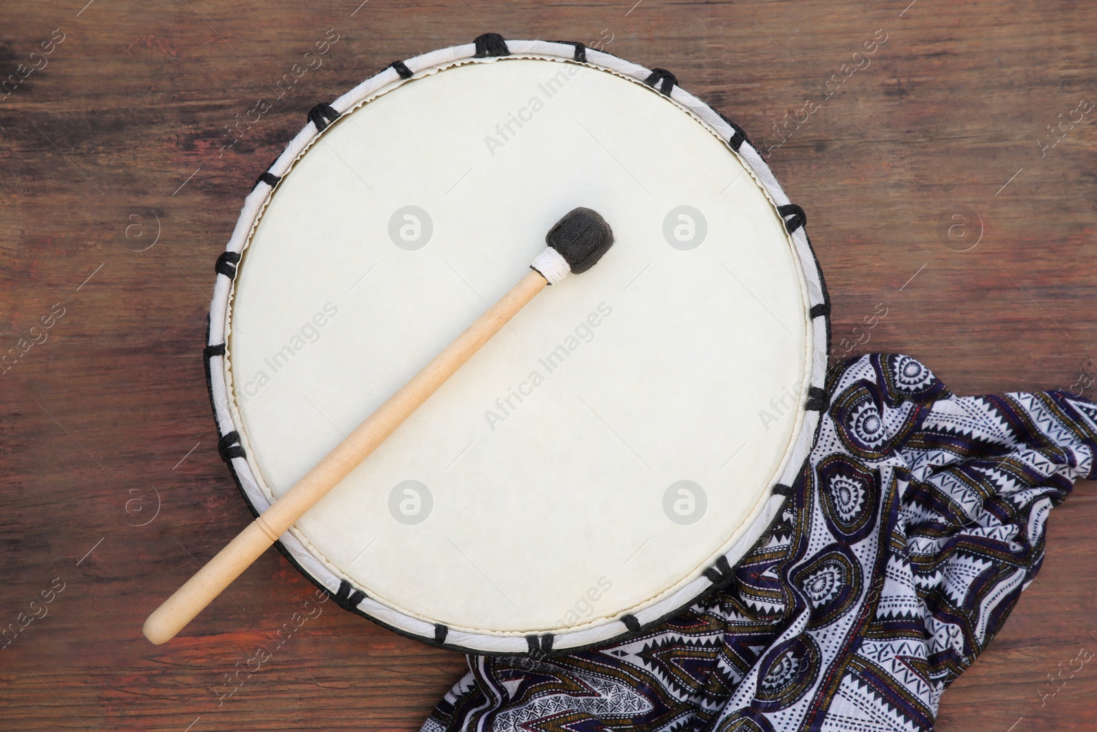 Photo of Modern drum with drumstick on wooden table, top view