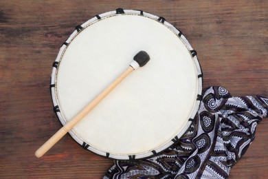 Photo of Modern drum with drumstick on wooden table, top view