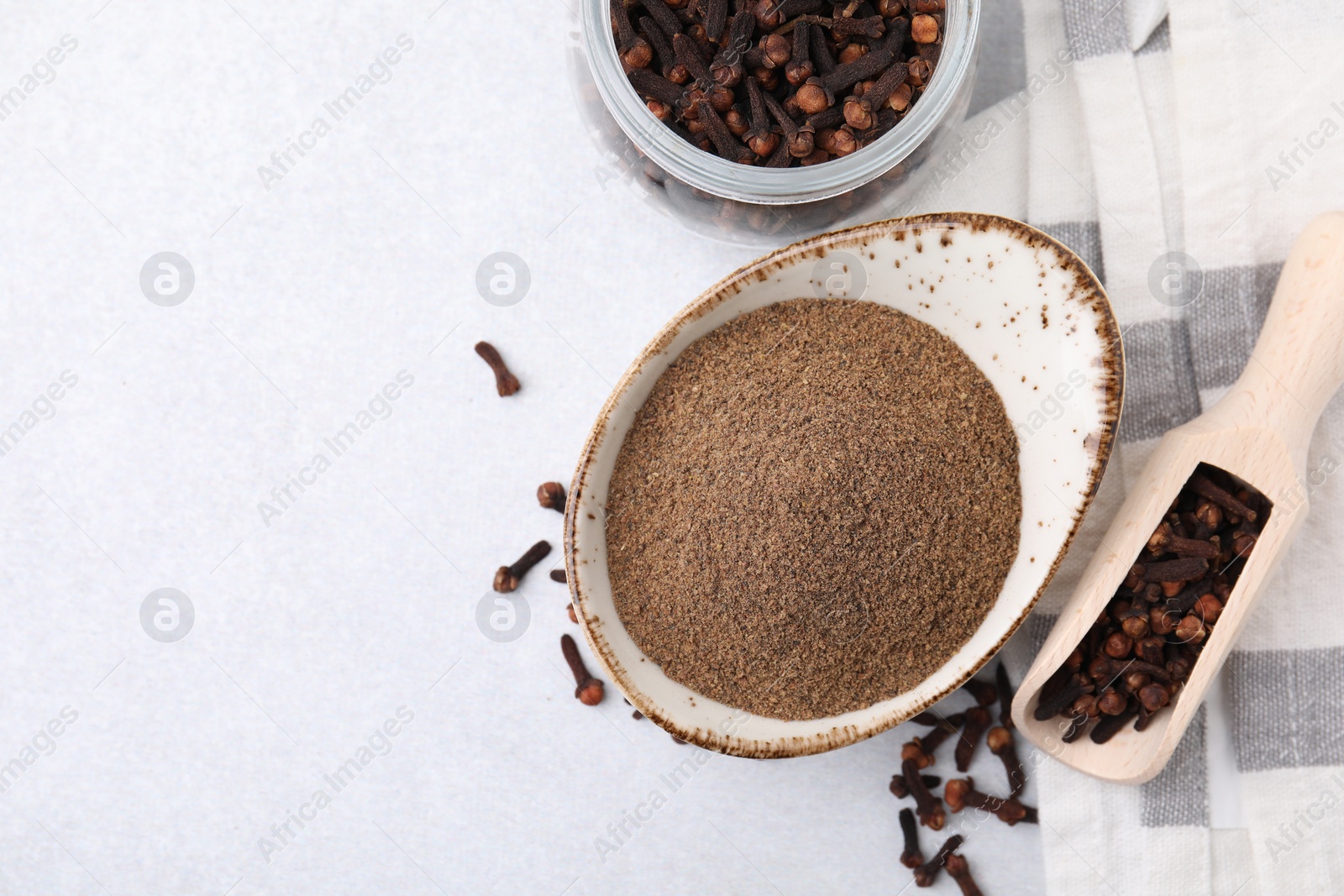 Photo of Aromatic clove powder, scoop and dried buds on light table, flat lay. Space for text