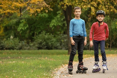 Photo of Happy children roller skating in autumn park. Space for text