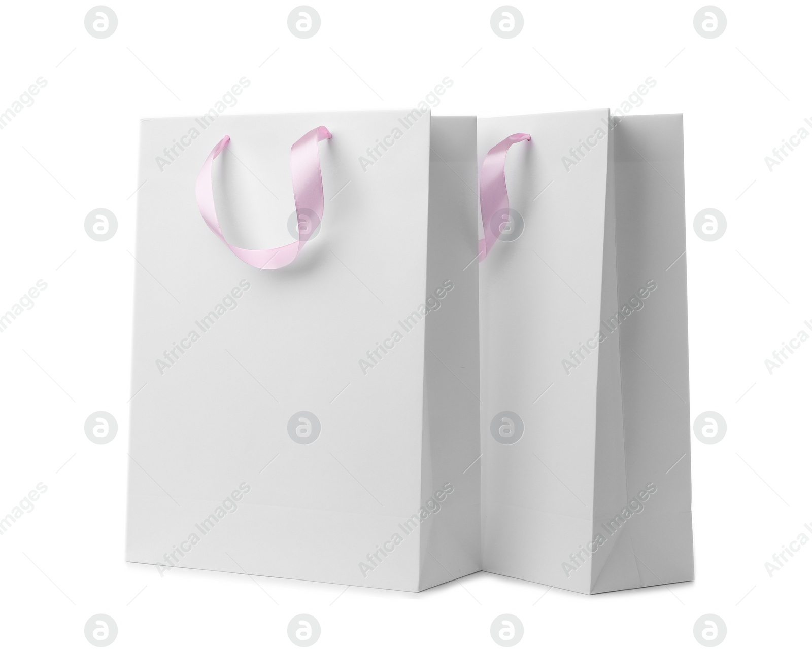 Photo of Paper shopping bags with ribbon handles on white background. Mockup for design