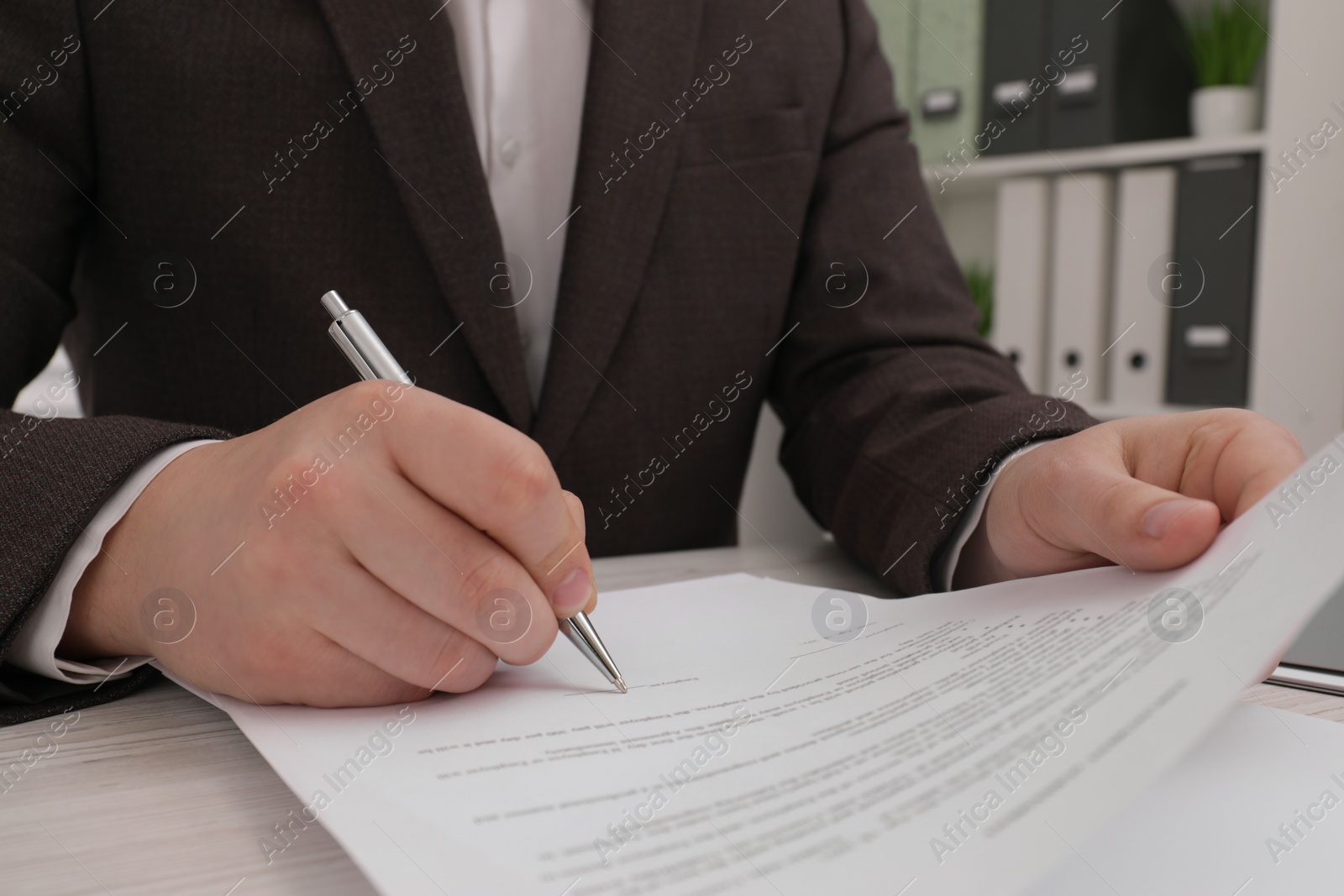 Photo of Man signing document at wooden table, closeup