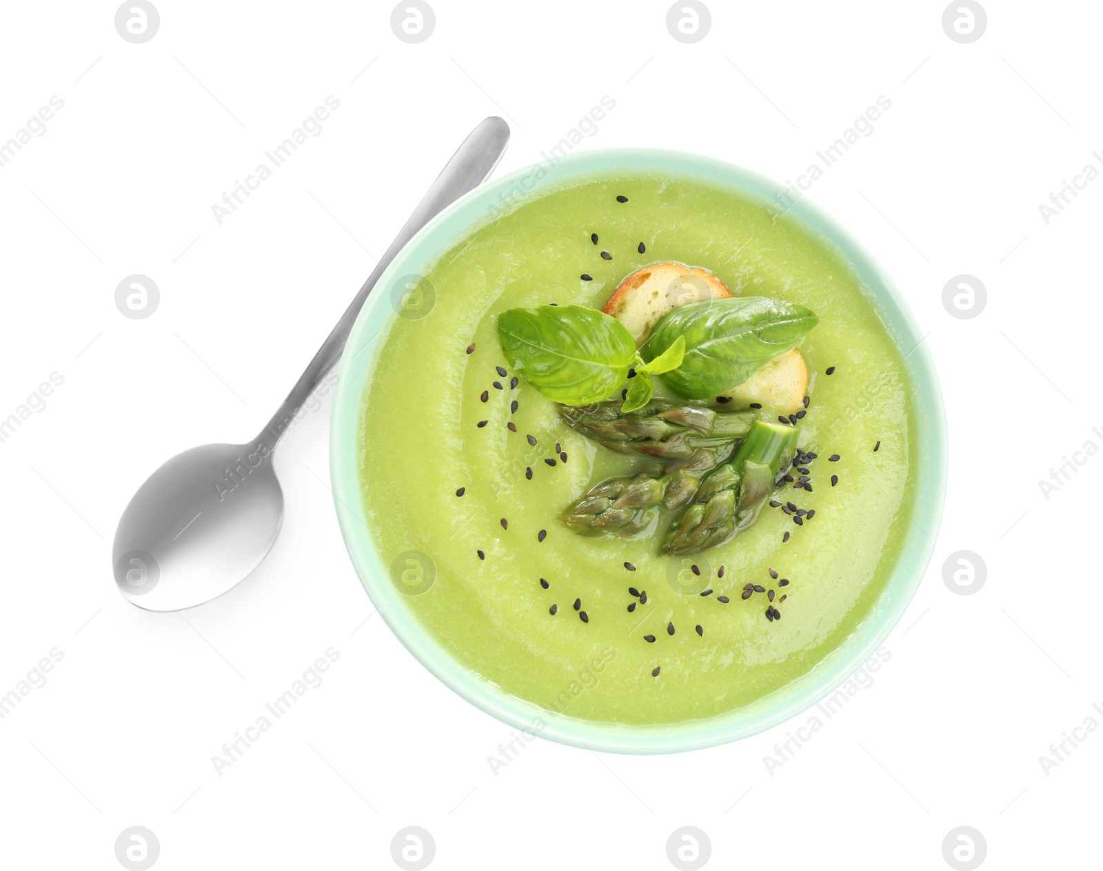 Photo of Delicious asparagus soup with basil and sesame seeds isolated on white, top view