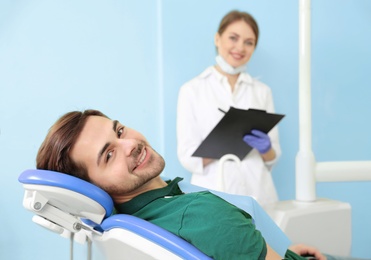 Photo of Happy patient and dentist in modern clinic, space for text
