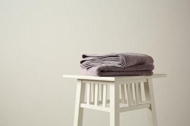 Photo of Violet towels on stool indoors. Space for text
