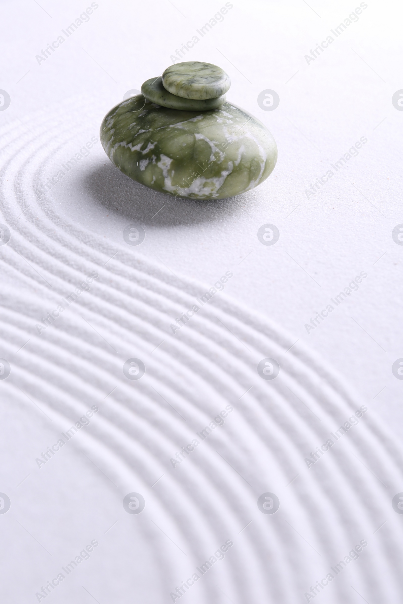 Photo of Zen garden stones on white sand with pattern. Space for text