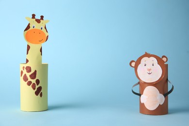 Photo of Toy monkey and giraffe made from toilet paper hubs on light blue background, space for text. Children's handmade ideas