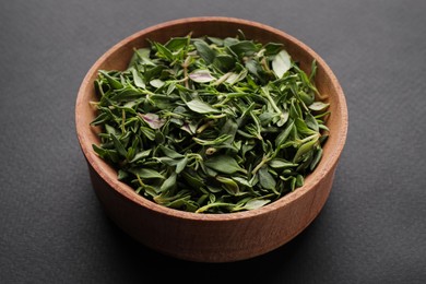 Photo of Wooden bowl of fresh green thyme leaves on dark background
