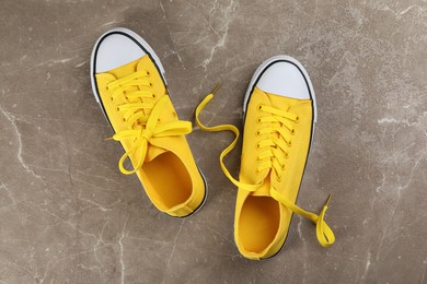 Photo of Pair of yellow sneakers on grey stone table, flat lay