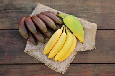 Different sorts of bananas on wooden table, top view