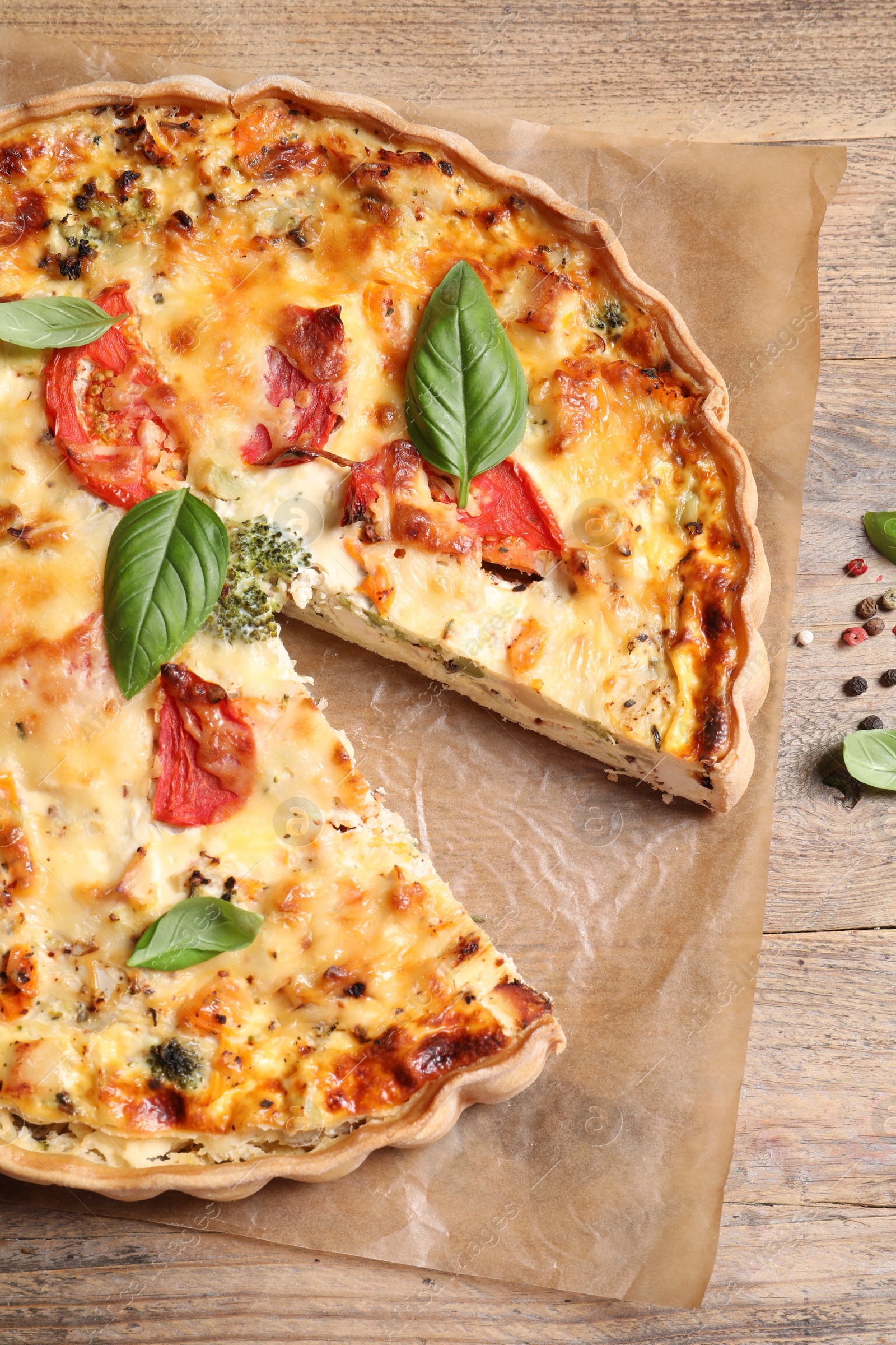 Photo of Tasty quiche with tomatoes, basil and cheese on wooden table, flat lay