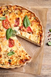 Photo of Tasty quiche with tomatoes, basil and cheese on wooden table, flat lay