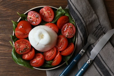 Delicious burrata cheese with tomatoes and basil served on wooden table, flat lay