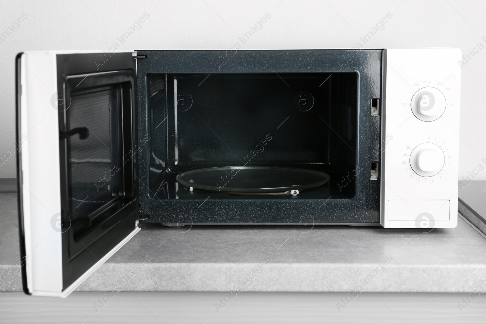 Photo of Open modern microwave oven on table in kitchen