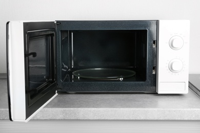 Open modern microwave oven on table in kitchen