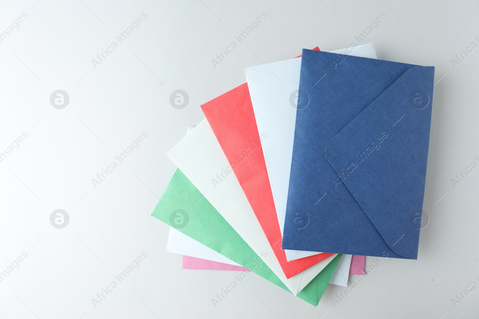 Photo of Colorful paper envelopes on light background, top view. Space for text