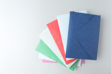 Photo of Colorful paper envelopes on light background, top view. Space for text
