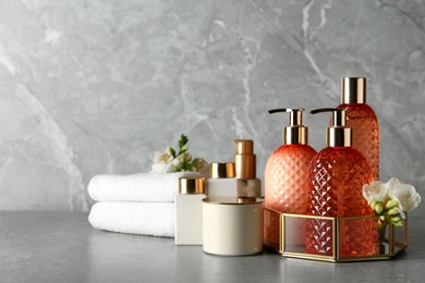 Photo of Stylish dispensers with liquid soap and other bathroom amenities on grey table, space for text