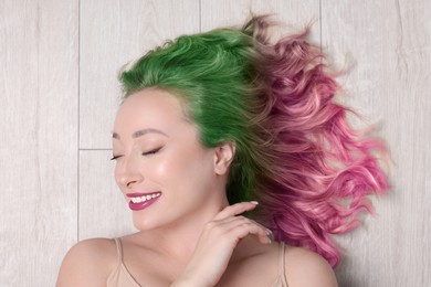Trendy hairstyle. Young woman with colorful dyed hair on white wooden background, top view