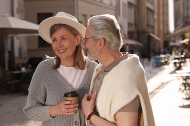 Photo of Affectionate senior couple with coffee walking outdoors, space for text