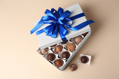 Box with delicious chocolate candies on beige background, above view