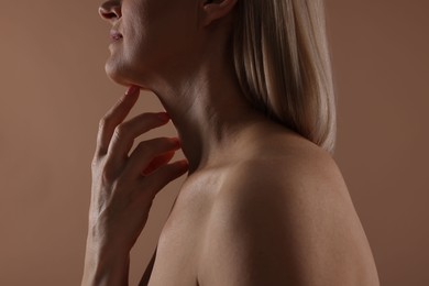 Photo of Woman touching her neck on beige background, closeup