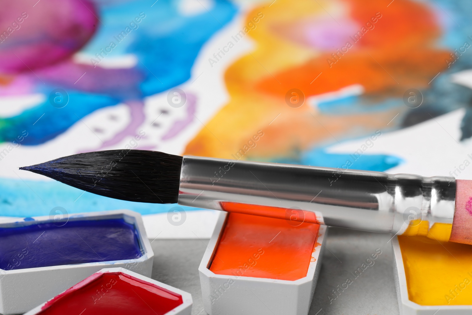 Photo of Abstract watercolor painting, colorful paints and brush on grey table, closeup