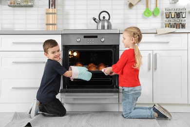 Little kids baking buns in oven at home