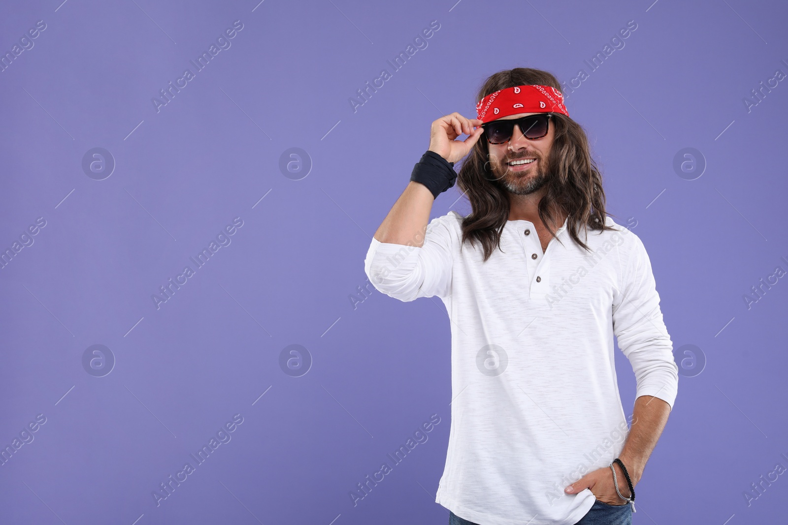 Photo of Stylish hippie man in sunglasses on violet background, space for text