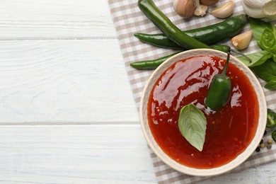 Photo of Spicy chili sauce and ingredients on white wooden table, top view. Space for text