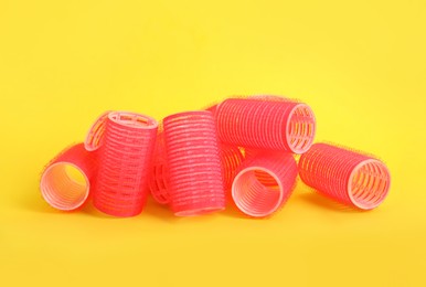 Many red hair curlers on yellow background