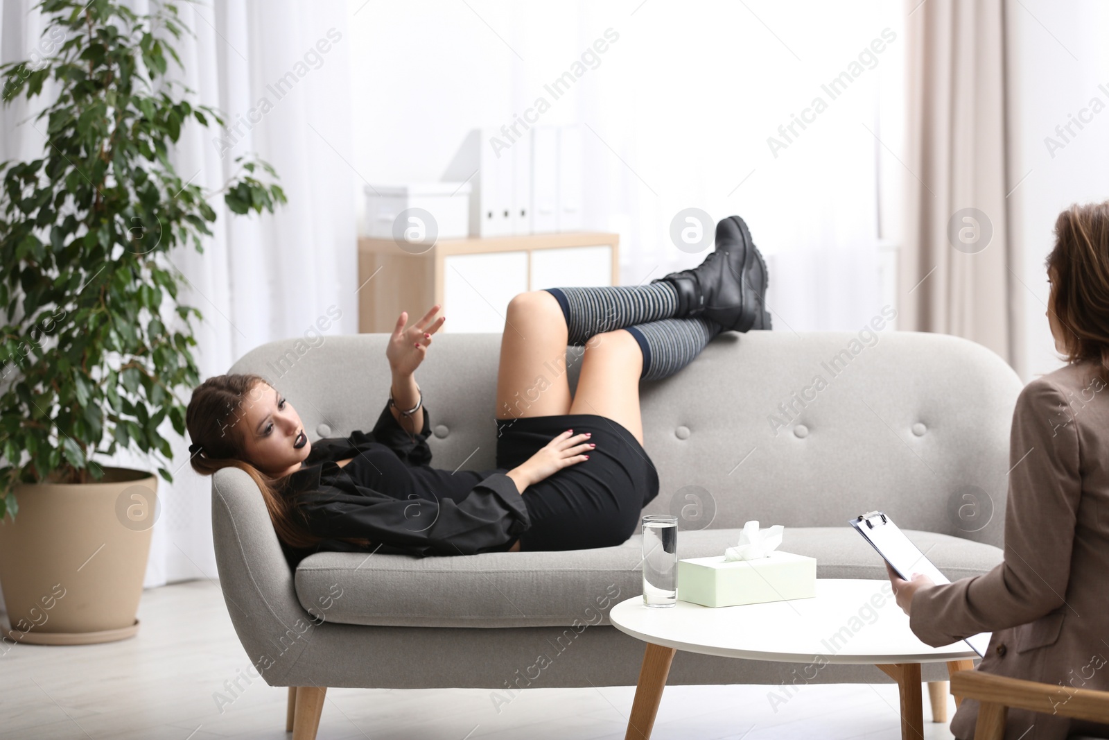 Photo of Psychotherapist working with teenage goth girl in office
