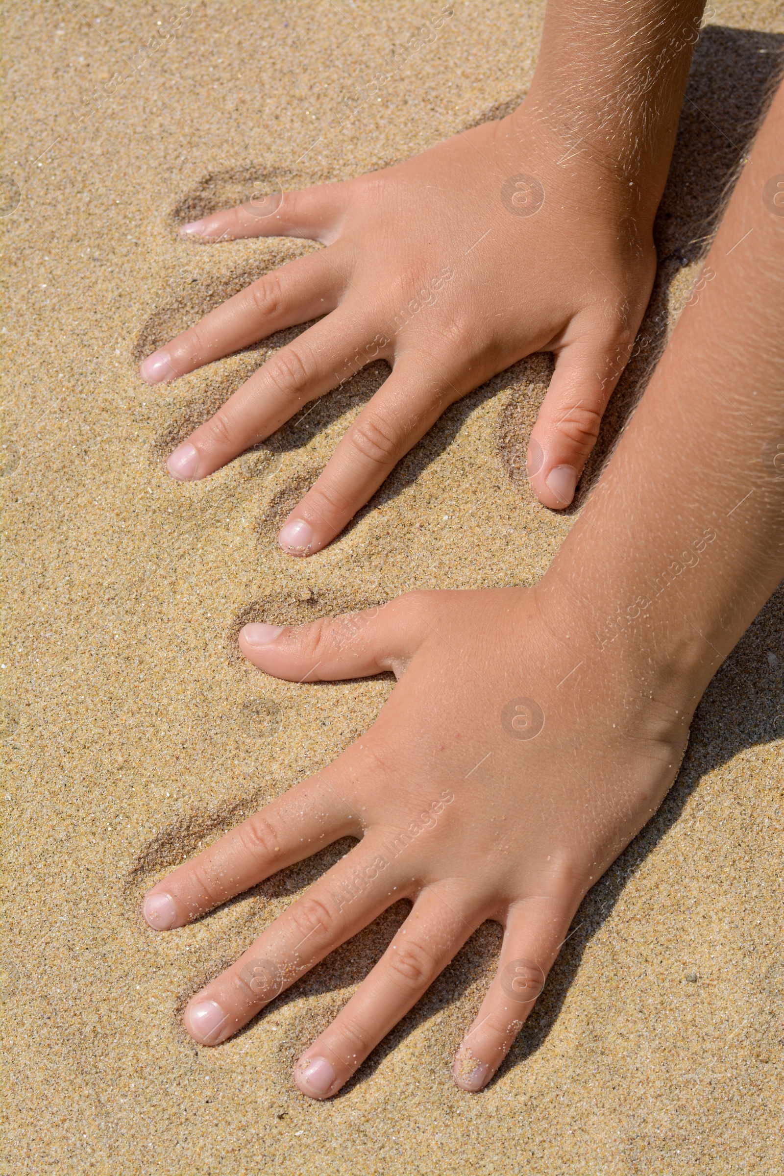 Photo of Child leaving handprints on sand outdoors, closeup. Fleeting time concept