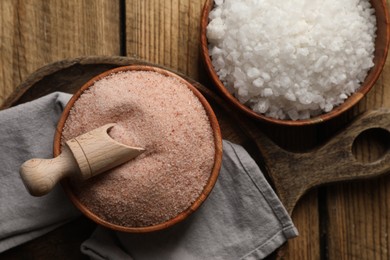 Photo of Different natural salt on wooden table, flat lay