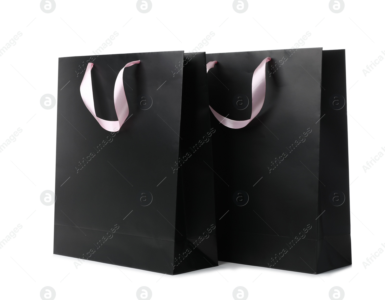 Photo of Paper shopping bags with ribbon handles on white background. Mockup for design