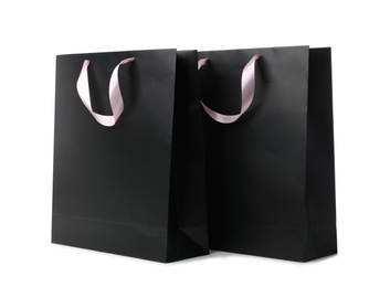 Paper shopping bags with ribbon handles on white background. Mockup for design