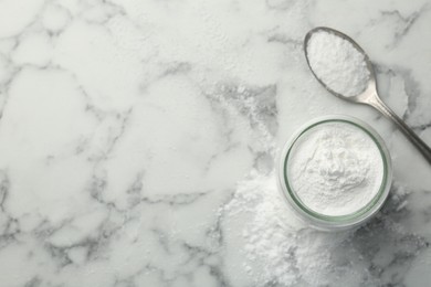 Baking powder in jar and spoon on white marble table, top view. Space for text