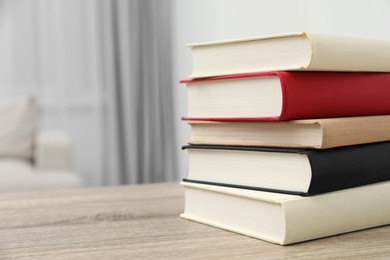 Photo of Stack of hardcover books on wooden table indoors. Space for text