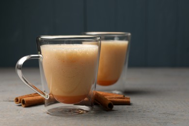 Photo of Delicious eggnog with cinnamon on grey wooden table