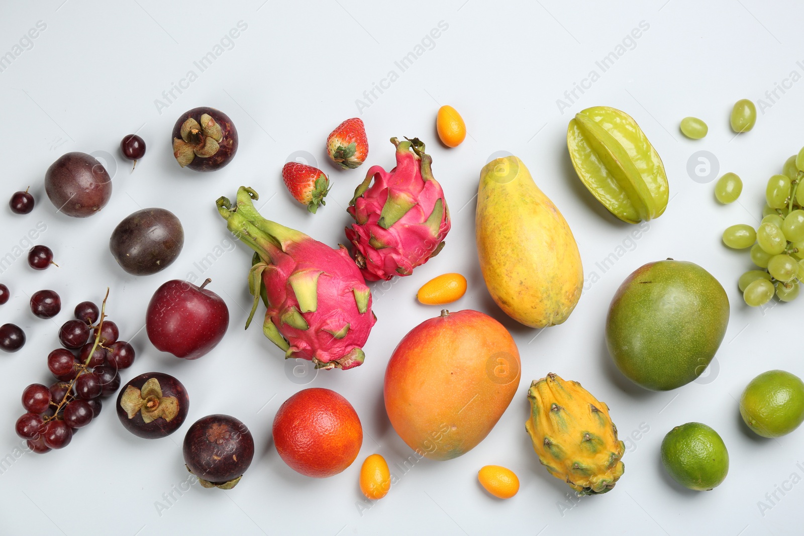 Photo of Many different delicious exotic fruits on light background, flat lay