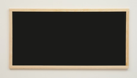 Photo of Clean black chalkboard hanging on white wall