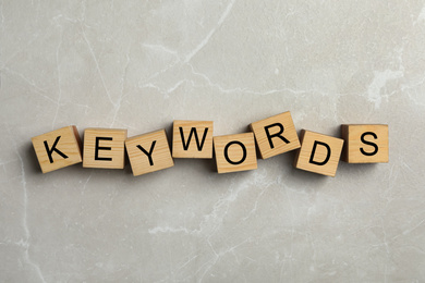 Photo of Word KEYWORD made of wooden cubes on marble background, flat lay